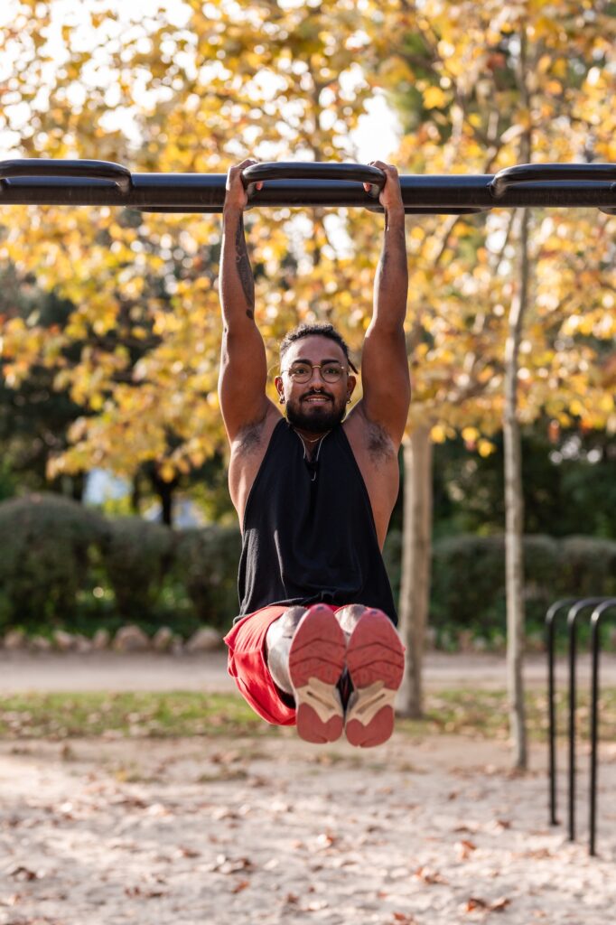 african american athlete boy does calisthenics fitness exercises on bars in park