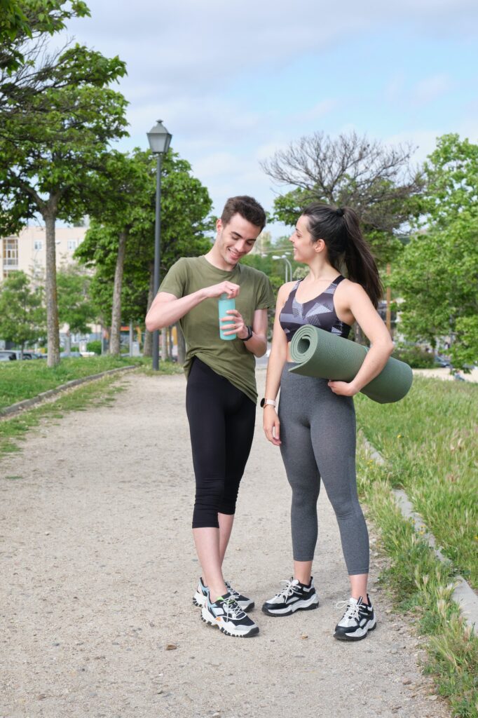 Young sport couple laughing standing at a park. Fitness concept.